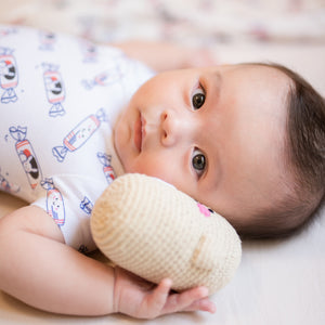 cute baby playing with doll and wearing the wee bean organic cotton onesie romper bodysuit in white rabbit candy